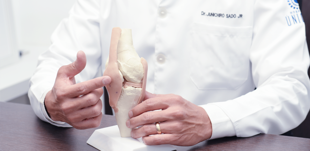 Close das mãos do médico ortopedista especialista em joelho em uma prótese do joelho